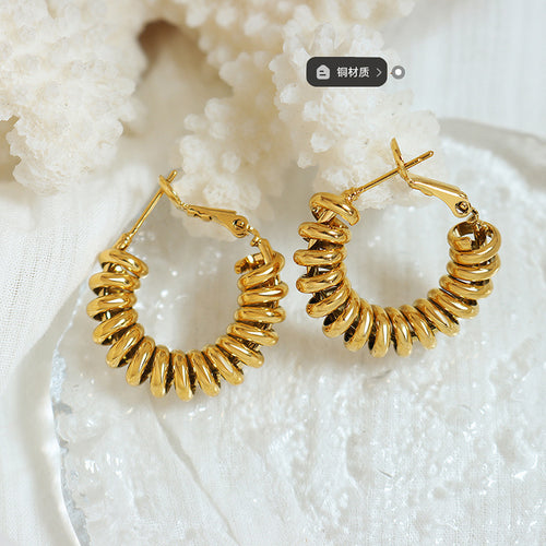 Pair of gold spiral coil U-hoops flat lay with coral and copper label