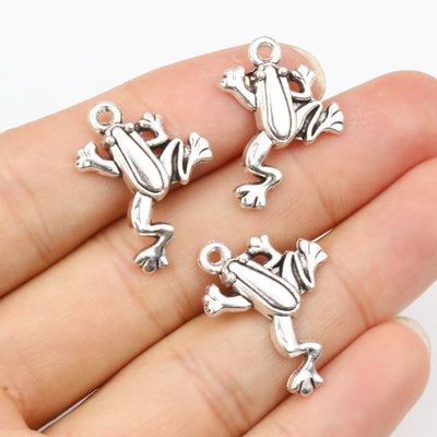 Antique silver-tone frog charm with raised body detail in a group view on a white background