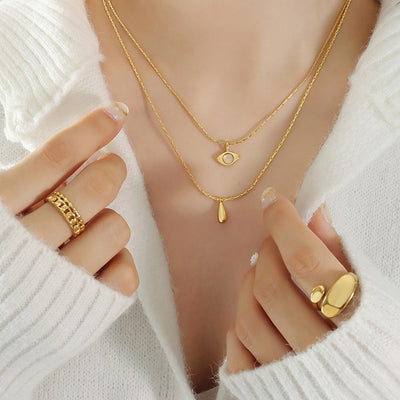 Gold double layer eye and teardrop necklace worn with white sweater