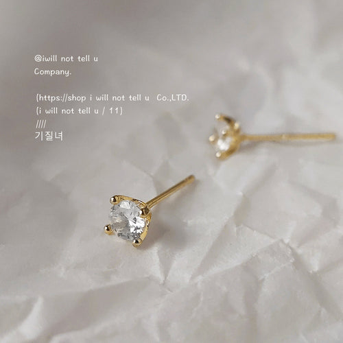Gold four-prong clear crystal studs on crumpled white paper