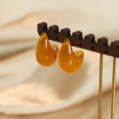 Pair of amber resin curved earrings on wooden display rack