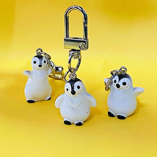 Three white penguin charms close-up, one hanging from silver clasp