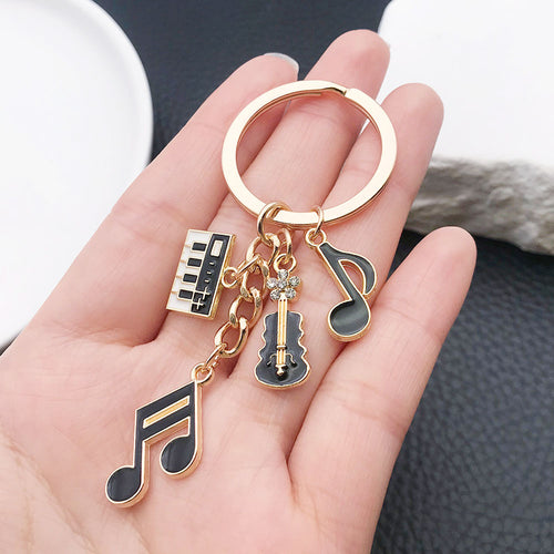 Styled close-up of piano violin and music note charm keychain showing colors and surface details