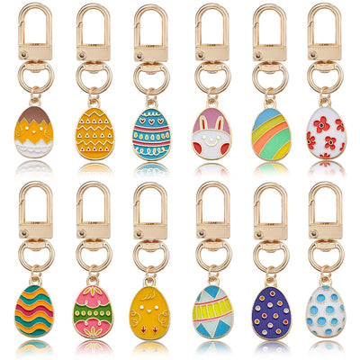 Front-facing grid of twelve gold-tone clasp keychains with assorted egg-shaped charms.