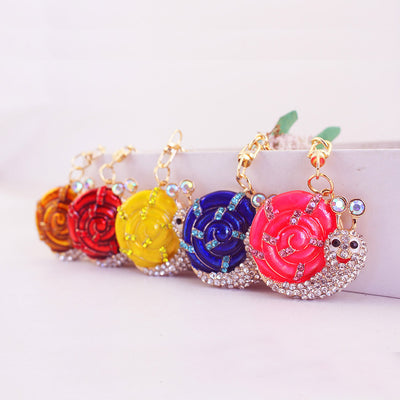 Five rhinestone snail keychains displayed in orange, red, yellow, blue, and pink.