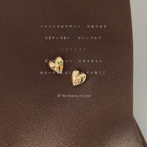 Gold mini polished heart studs on brown satin fabric surface