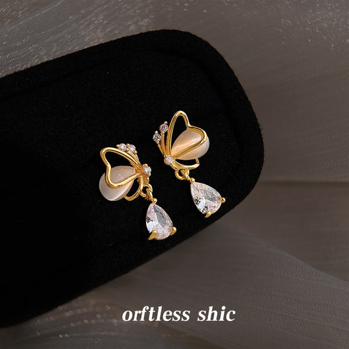 Gold cream butterfly studs with clear drops on black velvet