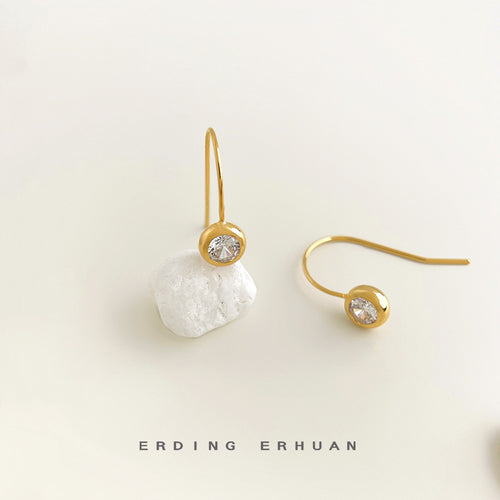 Single gold bezel CZ hook resting on white stone