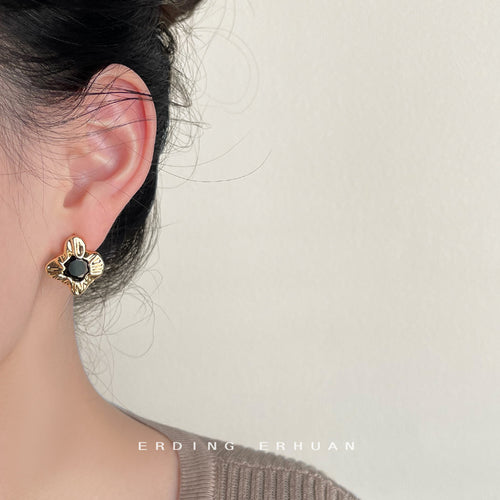Gold petal black center stud worn on ear side view