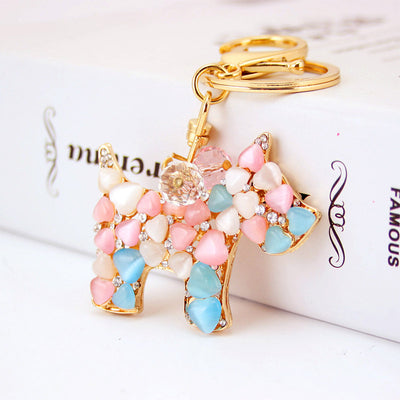 Front view of the dog keychain showing pink, blue, and white stones beside a split ring.