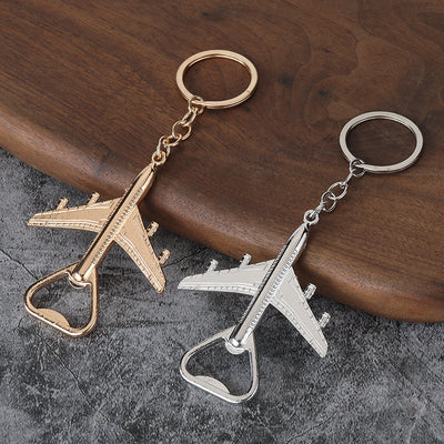 Silver-tone and gold-tone airplane opener keychains lie side by side.