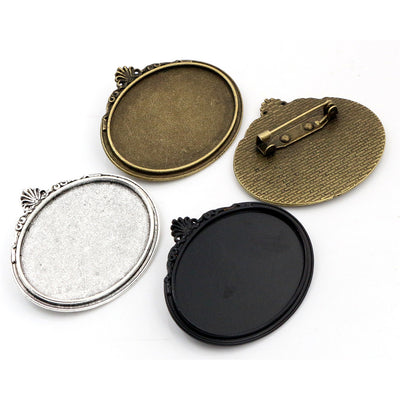 Overview of oval recessed trays with floral edging, top bails, and pin backs in four finishes