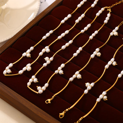 Multiple gold tube pearl necklaces and bracelets in velvet tray