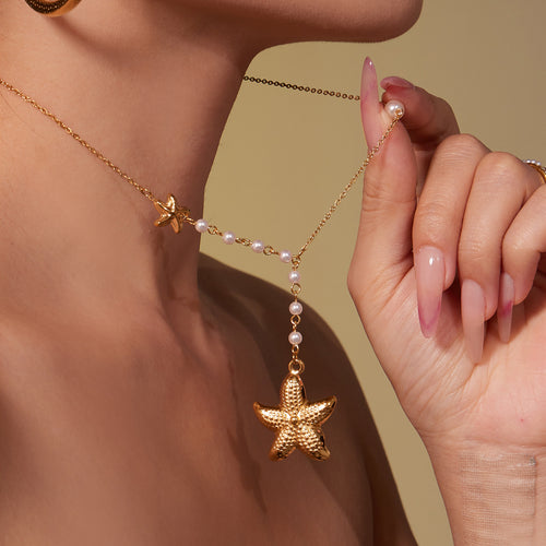 Neckline view of gold tone starfish and pearl lariat necklace in main image 2.