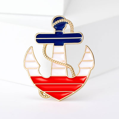 Front view of the anchor sailboat brooch showing a gold-tone anchor framing a red, white and blue enamel sailboat