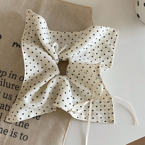white satin oversized bow hair tie with black polka dots and long tails shown worn in a styled second view