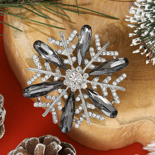 Black grey crystal snowflake brooch on wood with pinecones