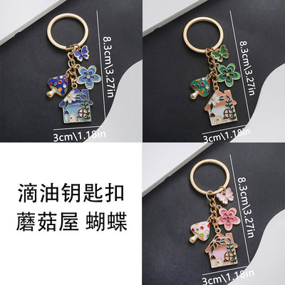 Front product photo of pink blue and green mushroom house butterfly keychain showing the pictured design arrangement