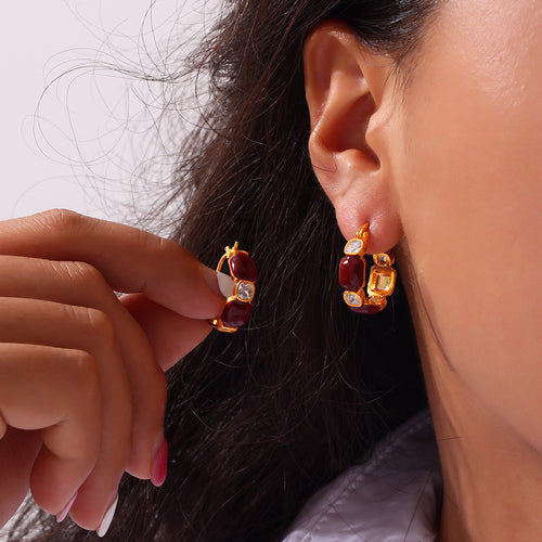 Model wearing gold burgundy hoop earrings with crystal accents near the ear