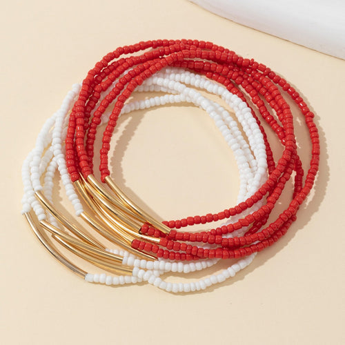 Red and white seed bead stretch bracelets coiled together showing gold tube bars