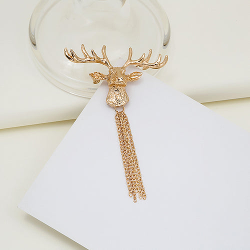 Gold deer head brooch with chain tassel on white card and glass base