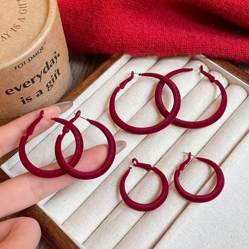 Close view of the colors and surface details on red and blue flocked hoop earrings