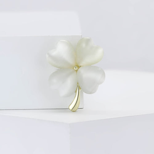 White cat-eye four-leaf clover brooch with gold stem on display