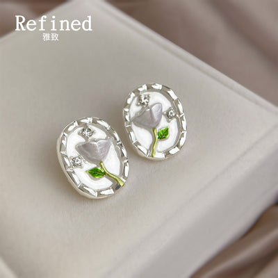 Clear oval-dome white tulip stud earrings on a pale display.