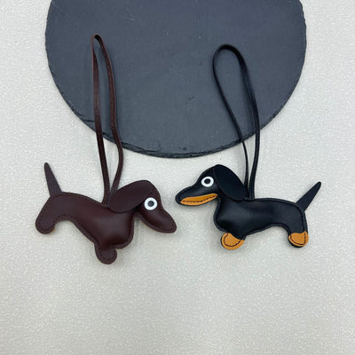 Two PU leather dachshund charms, one dark brown and one black, hanging by their leather loops