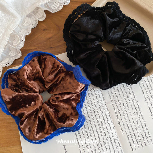 Coffee blue-edge and black velvet scrunchies on table with book