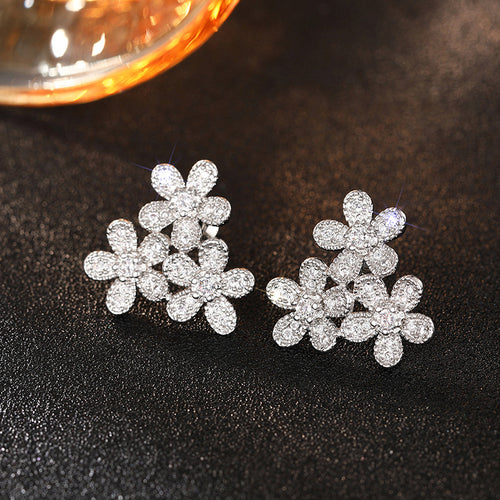 White metal triple flower pave cluster studs on dark surface