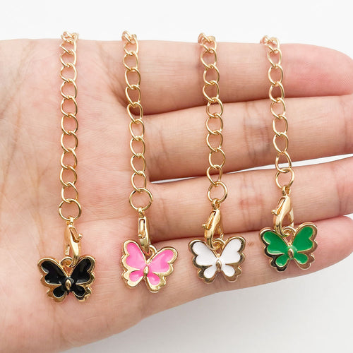 Image 2 showing a person holding four different colored butterfly charms.