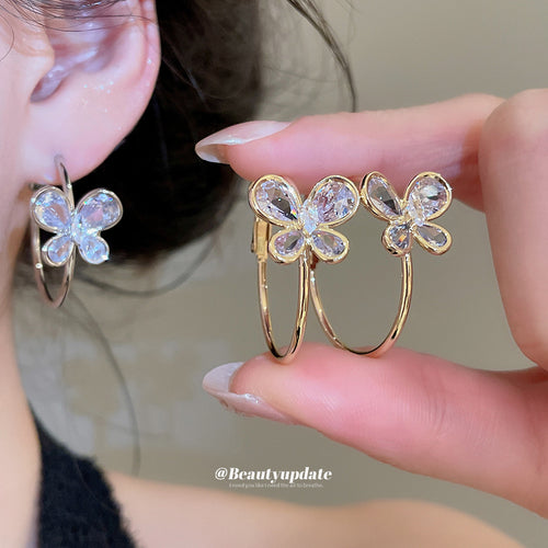 Styled view of crystal butterfly hoop earrings in silver and gold tones