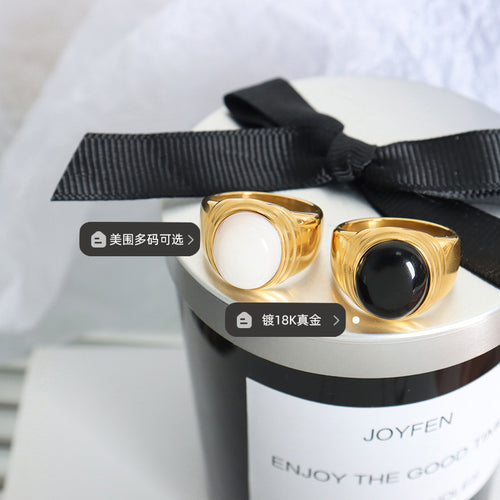 Gold black glass and white shell signet rings on gift box with labels