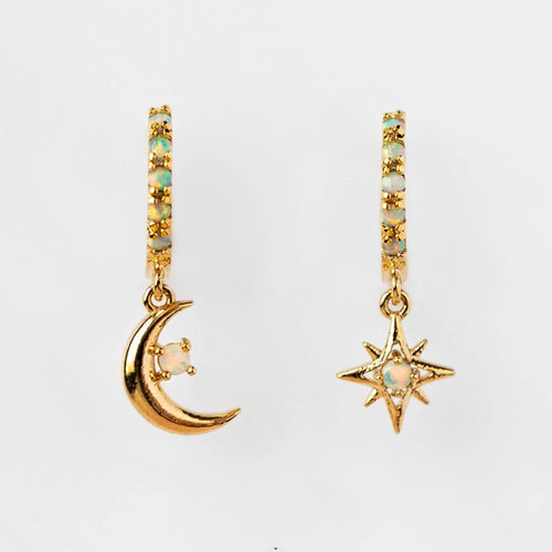 Pair of gold huggie hoops with moon and star charms on white background