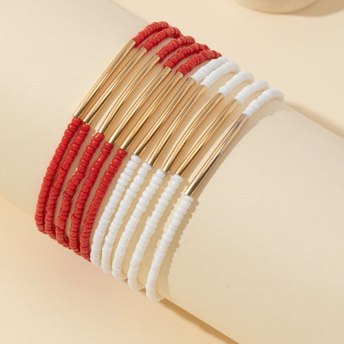 Red and white seed bead bracelets draped over a rolled cream paper prop