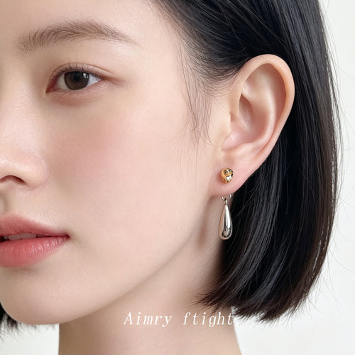 Two-tone gold and silver teardrop earring worn on ear profile