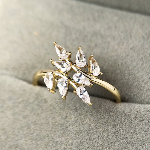 Gold leaf clear stone ring on gray fabric close-up