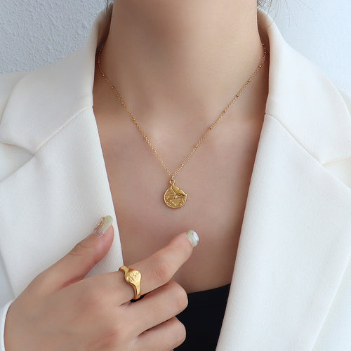 Model in white blazer wearing gold mermaid tail disc pendant necklace