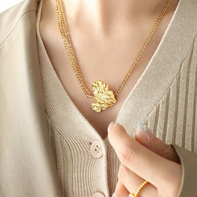 Gold dual-chain textured leaf pendant necklace worn on collarbone