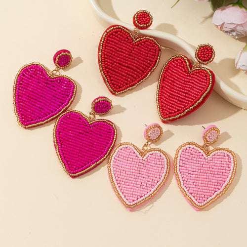 Rose, red and pink heart beaded drop earrings grouped together on cream background