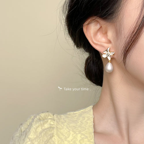 Model wearing gold cream enamel flower pearl drop on right earlobe