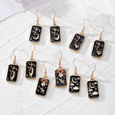 Five pairs of black enamel tarot rectangle drop earrings with gold hooks on white stone