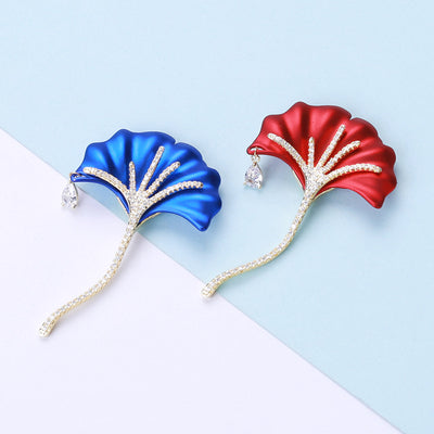 Blue and red enamel ginkgo leaf brooches with crystal stems on dual-tone backdrop