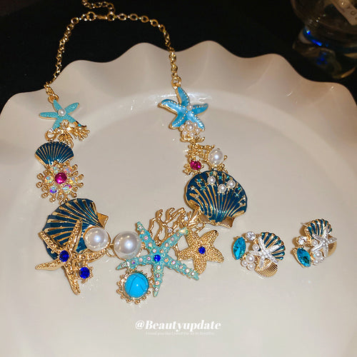 gold-tone blue starfish, shell, and coral necklace and earrings shown worn in a styled second view