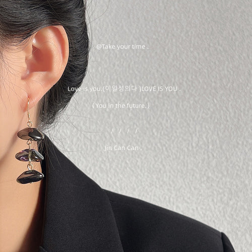 Dark glass triple drop earring worn on ear with black blazer