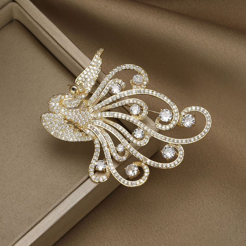 Gold phoenix brooch on beige fabric jewelry box angled view