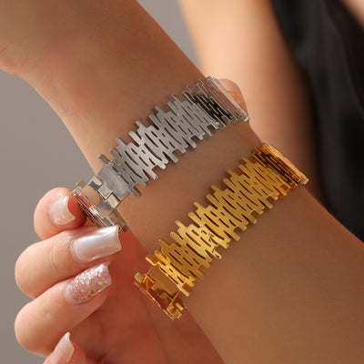 Steel and gold geometric cutout bracelets worn stacked on wrist