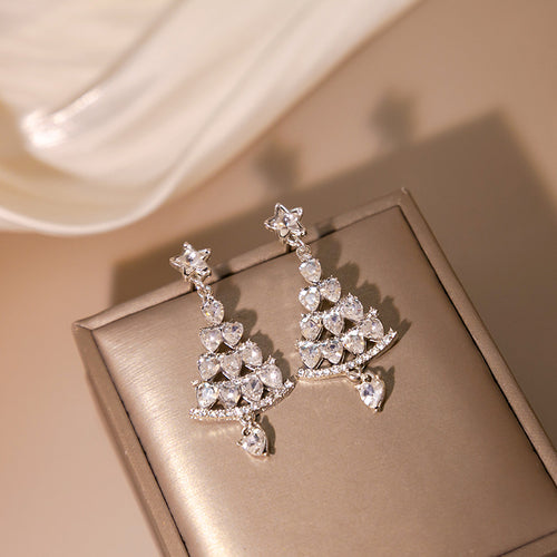Silver crystal Christmas tree star-post earrings on gray jewelry display block