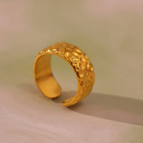 Close-up single gold hammered dimple open band ring on soft cloth
